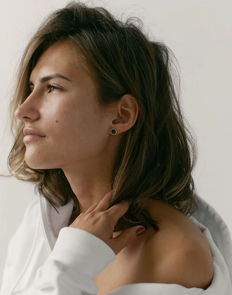 A profile shot of a person with short, wavy, light brown hair, wearing a white shirt. They are facing left with a serious expression. The lighting is soft, highlighting the details of their face and hair. - Kybella in Seattle, WA